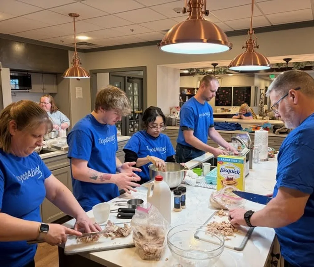 Company volunteers in matching shirts preparing food in the House kitchen.