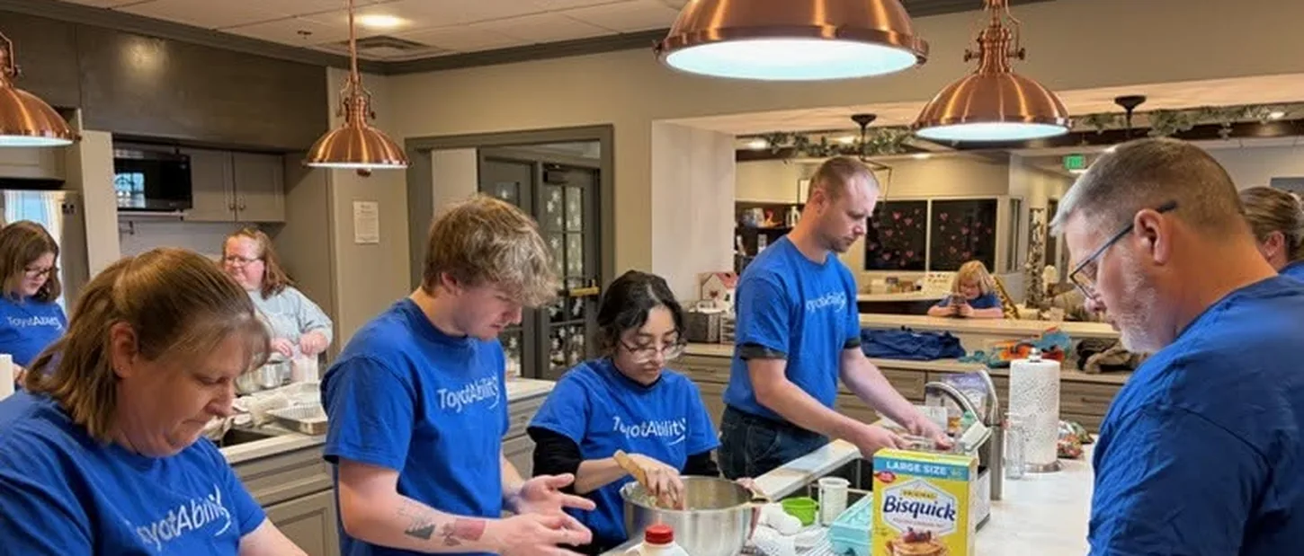 Company volunteers in matching shirts preparing food in the House kitchen.