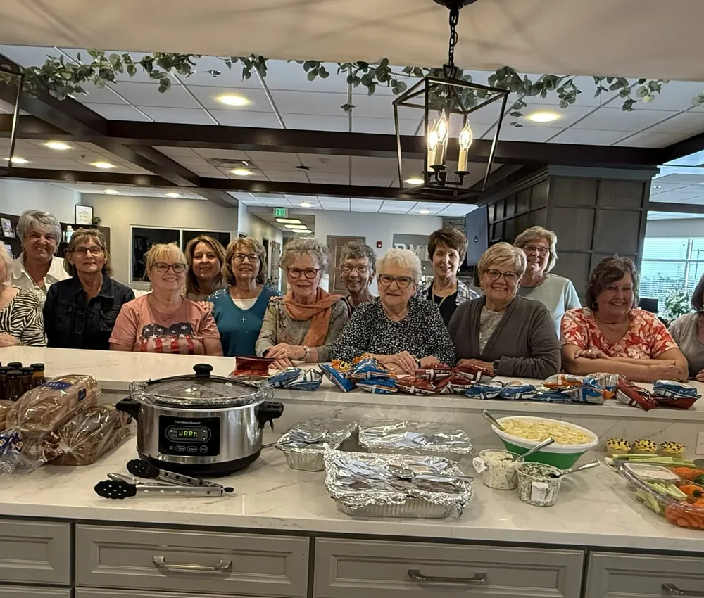 A homemakers group gathered behind a counter of prepared dishes in the House kitchen.