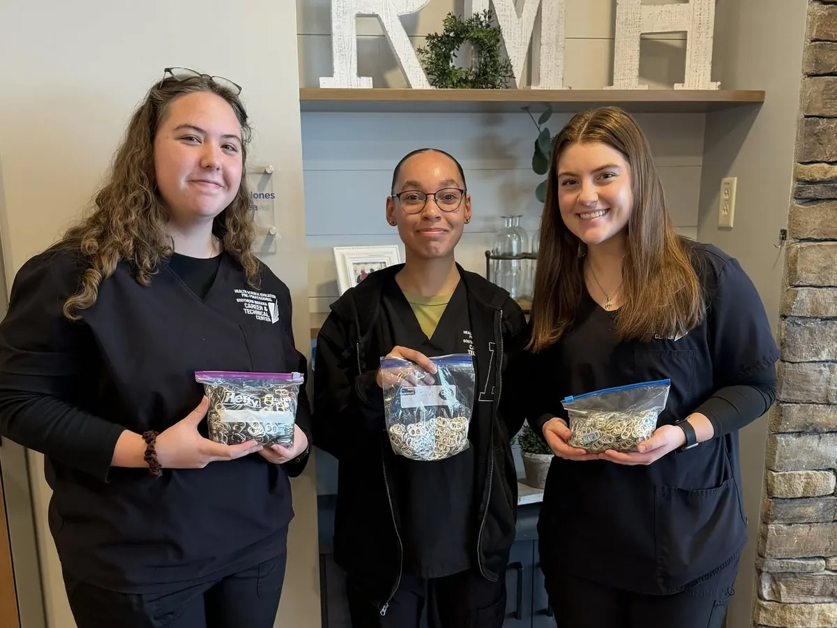 Three volunteers holding bags of collected pop tabs.
