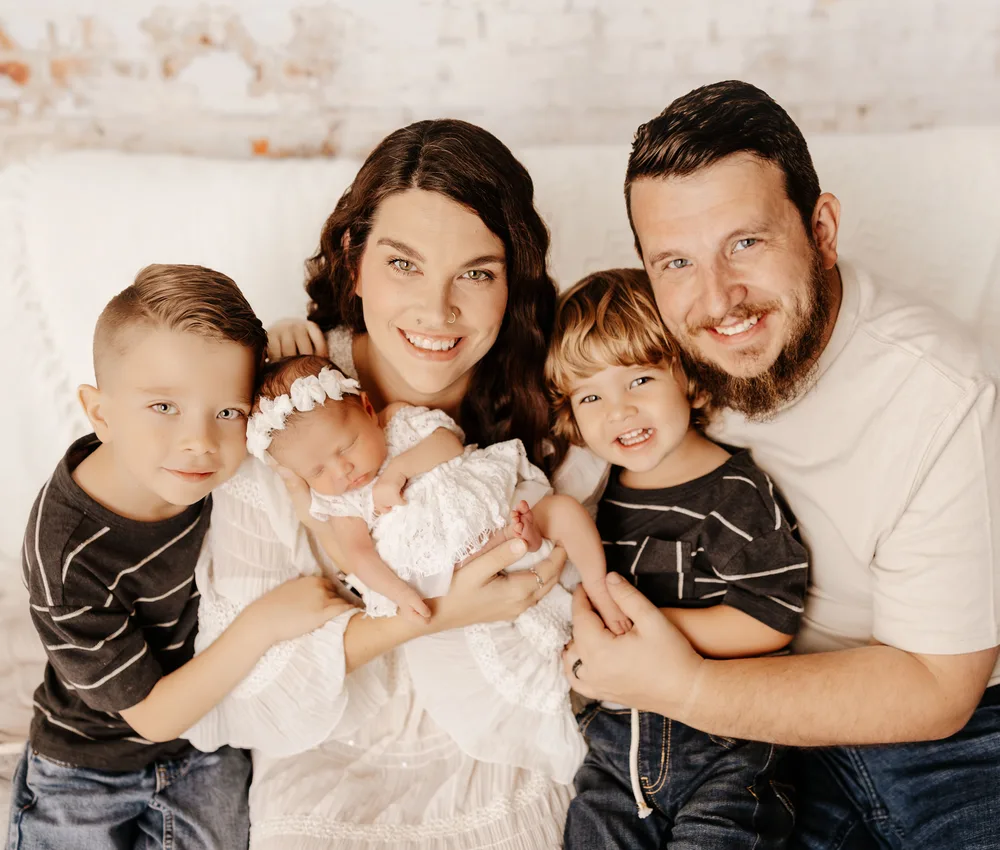 A smiling family holding their newborn baby.