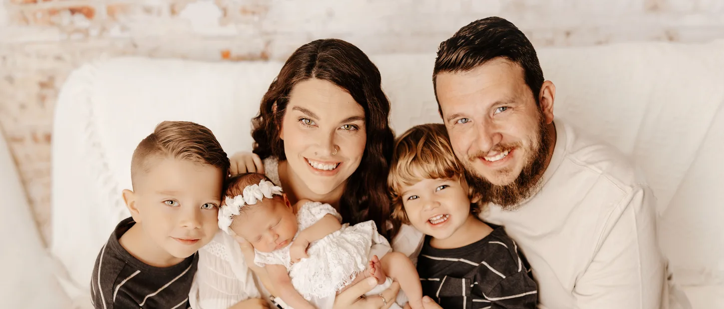 A smiling family holding their newborn baby.