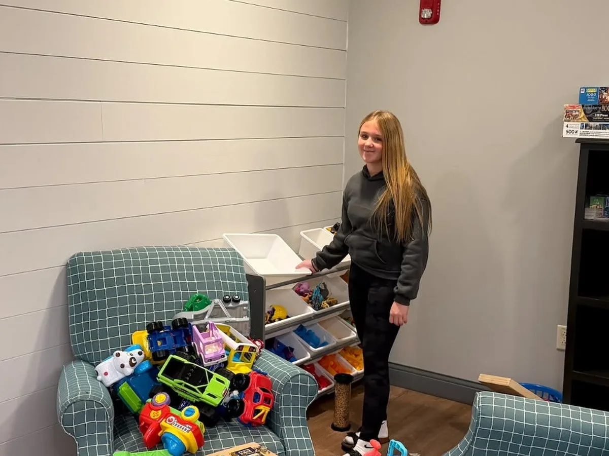 A student volunteer organizing toys in a House playroom.