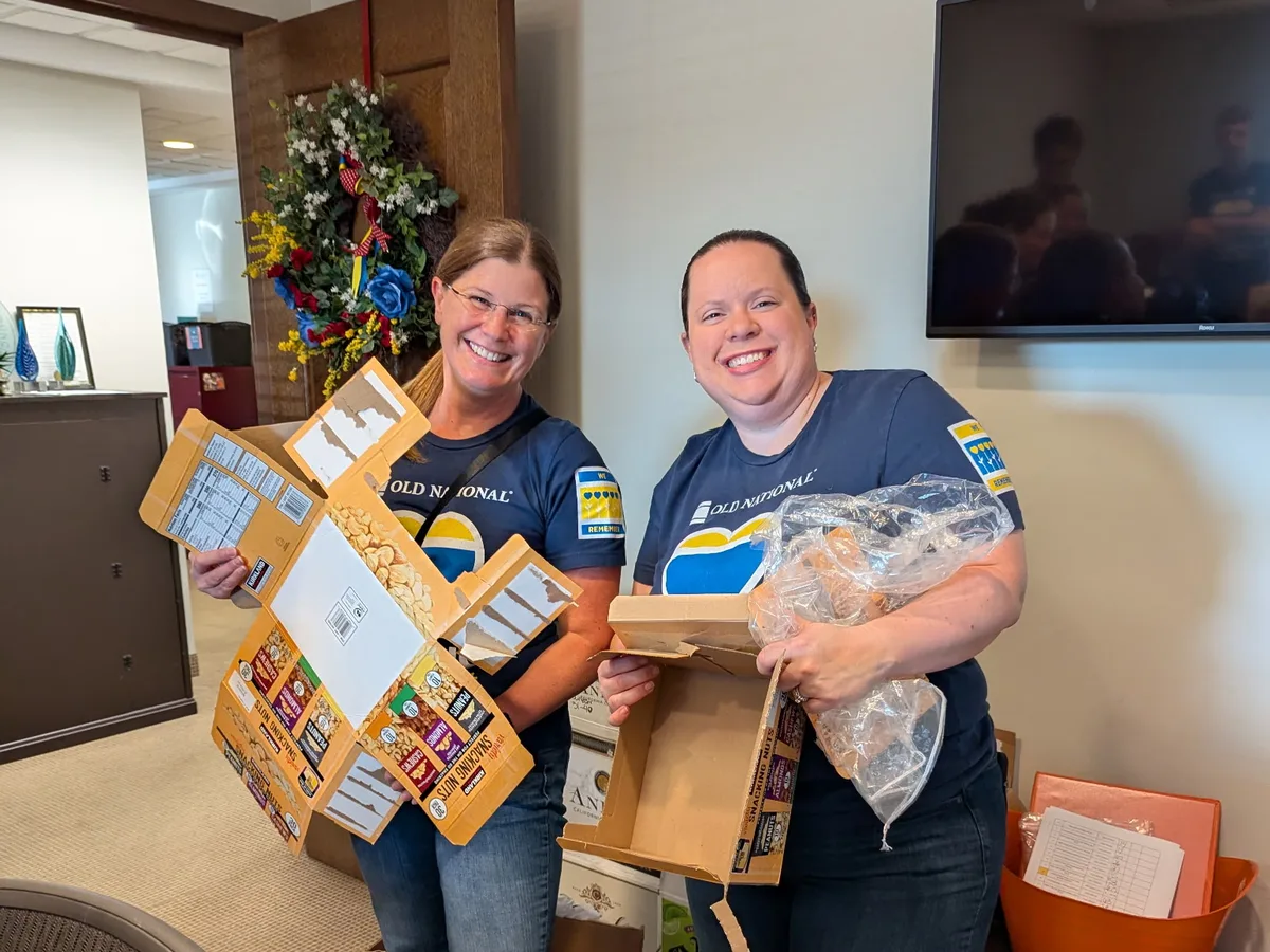 Two volunteers smiling while unpacking donations.