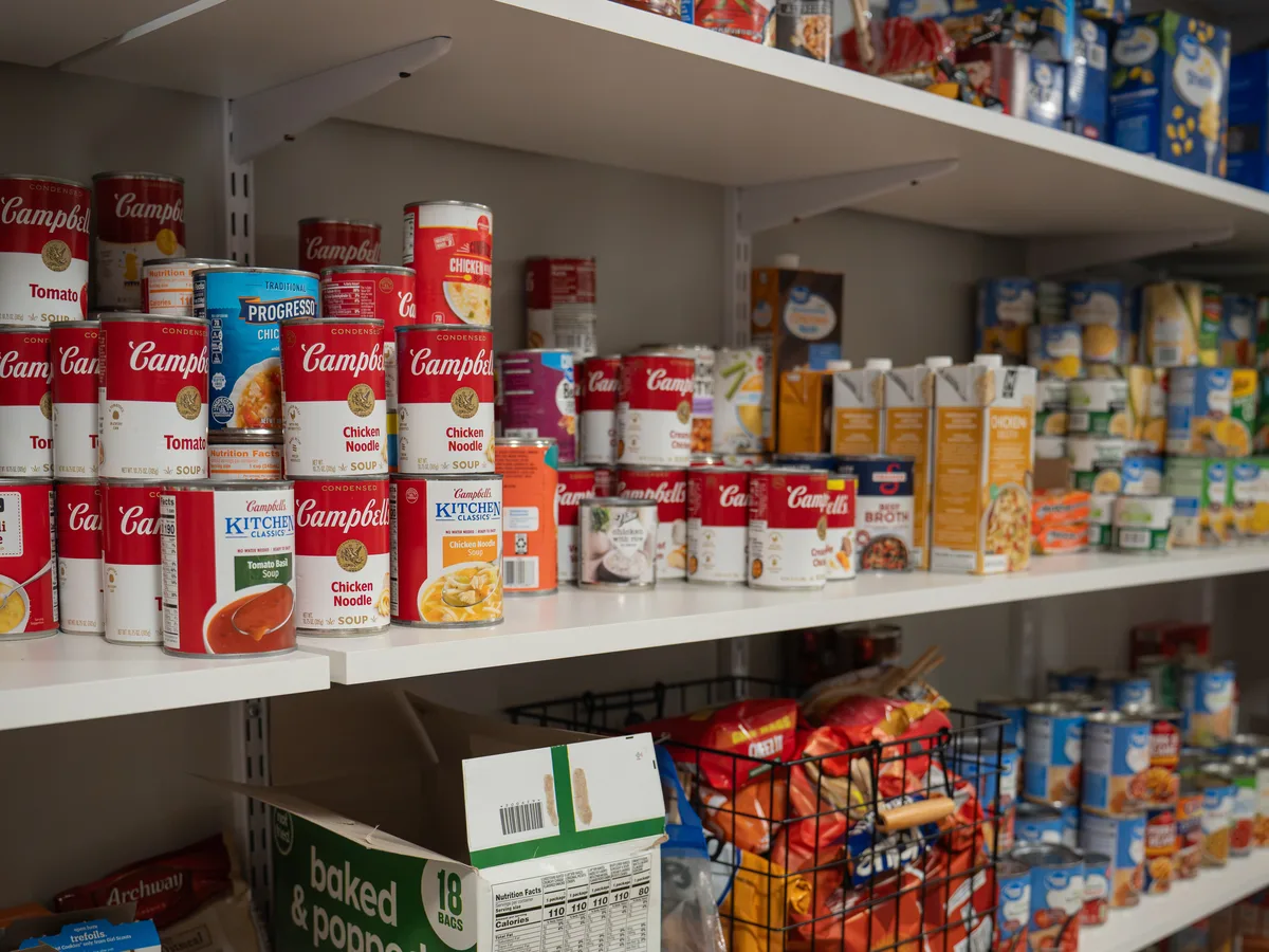 Pantry shelves stocked with donated soups, sauces, and snacks.